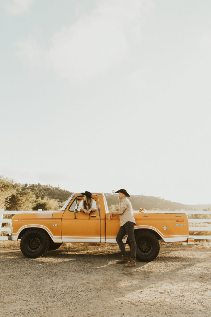 couple posing with their old ford truck for their western engagement photos