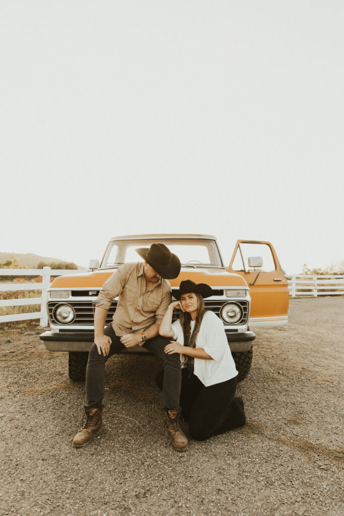 couple posing in front of their old ford truck for their western engagement photos