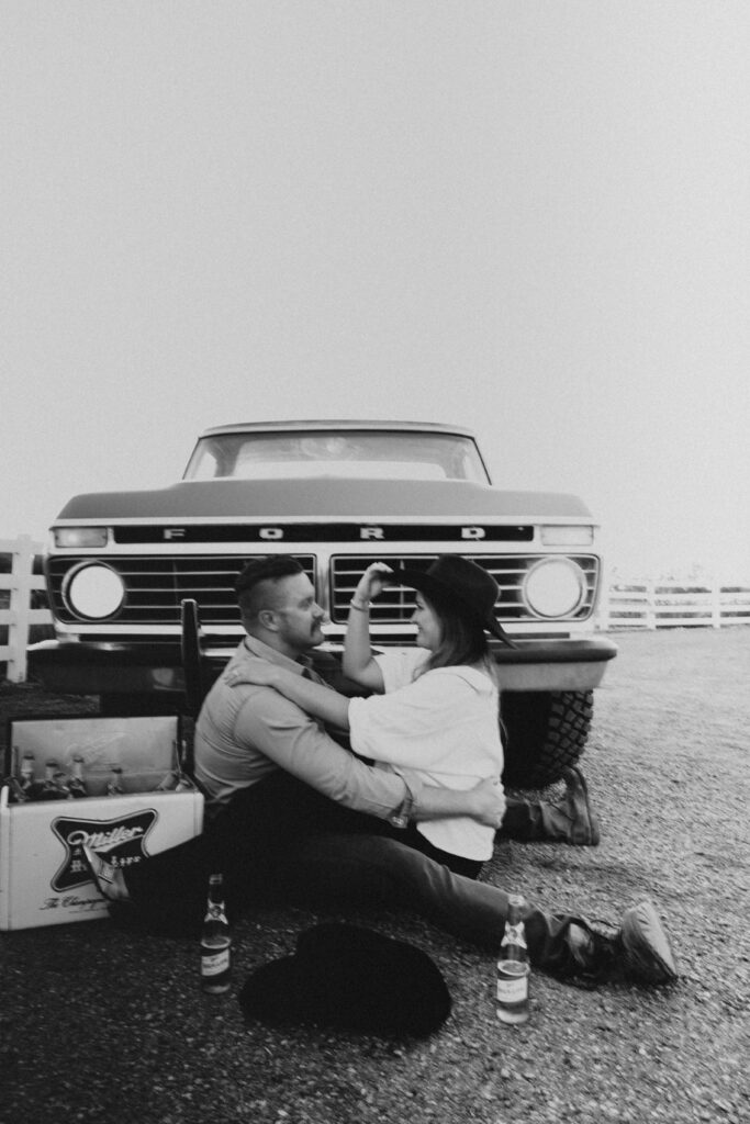 black and white image of couple posing in front of their old ford truck for their western engagement photography session